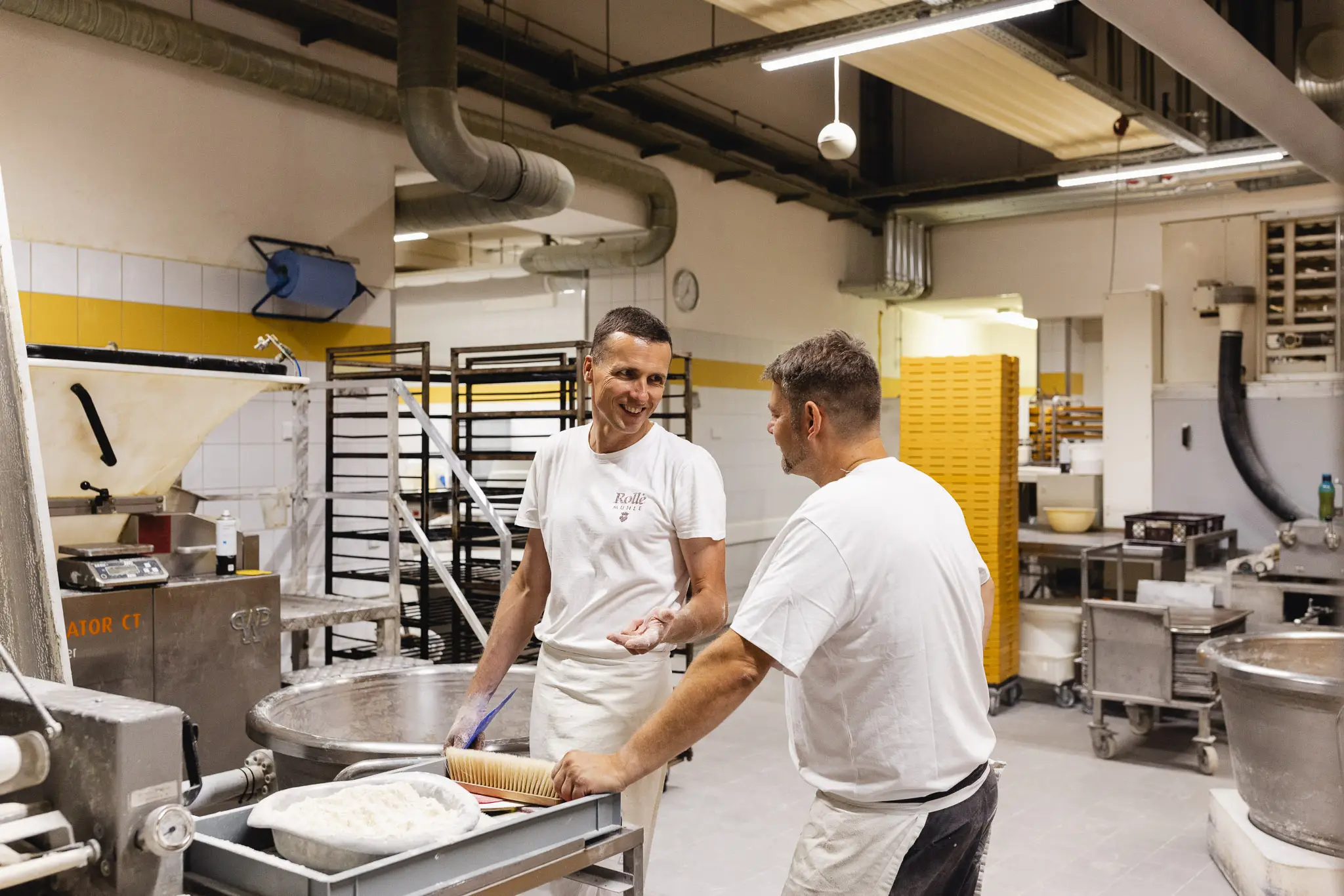 Zwei Bäcker unterhalten sich lächelnd während ihrer Arbeit in der Backstube.