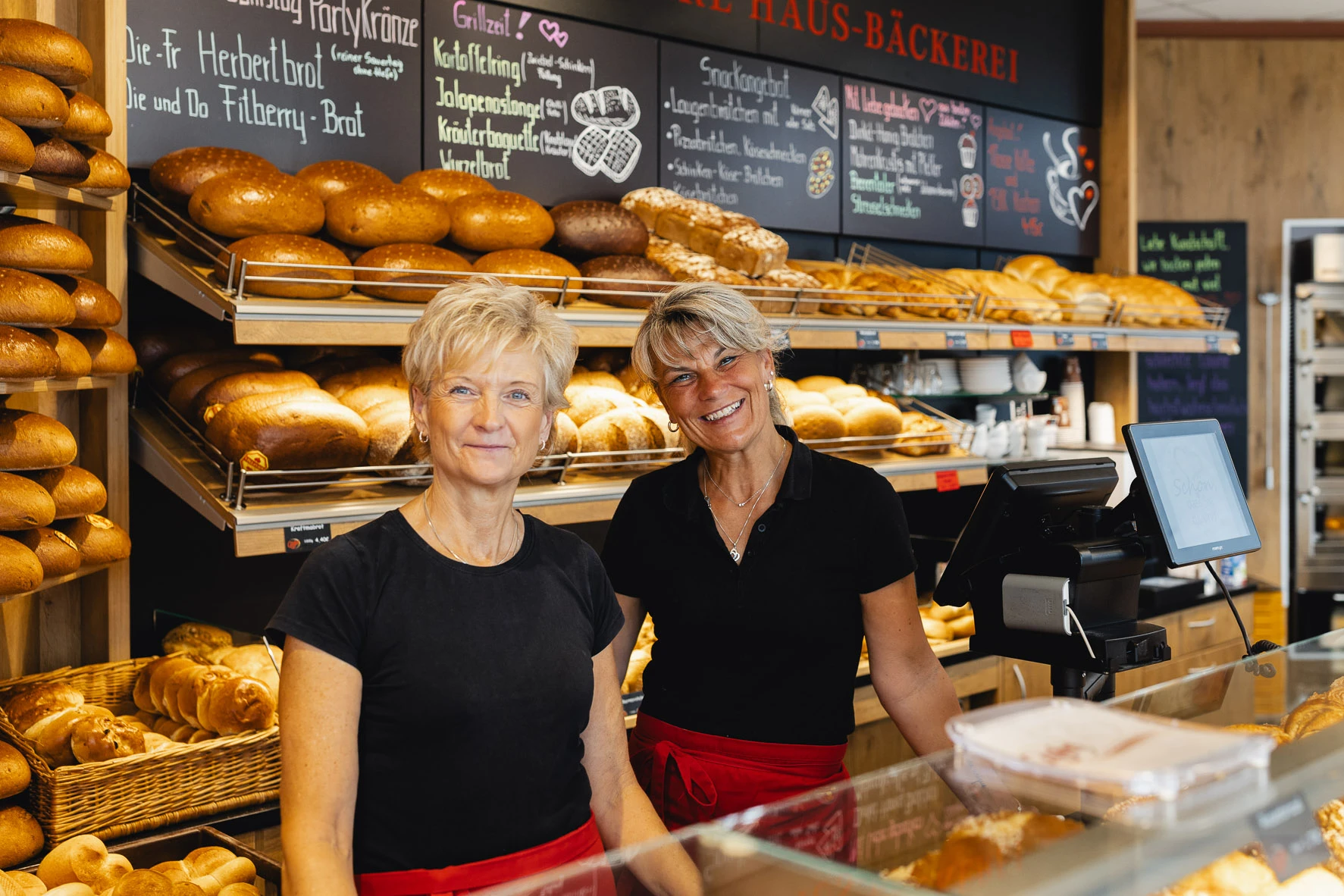 Zwei freundliche Mitarbeiterinnen der Bäckerei Göpfert lachen hinter der Theke herzlich in die Kamera.