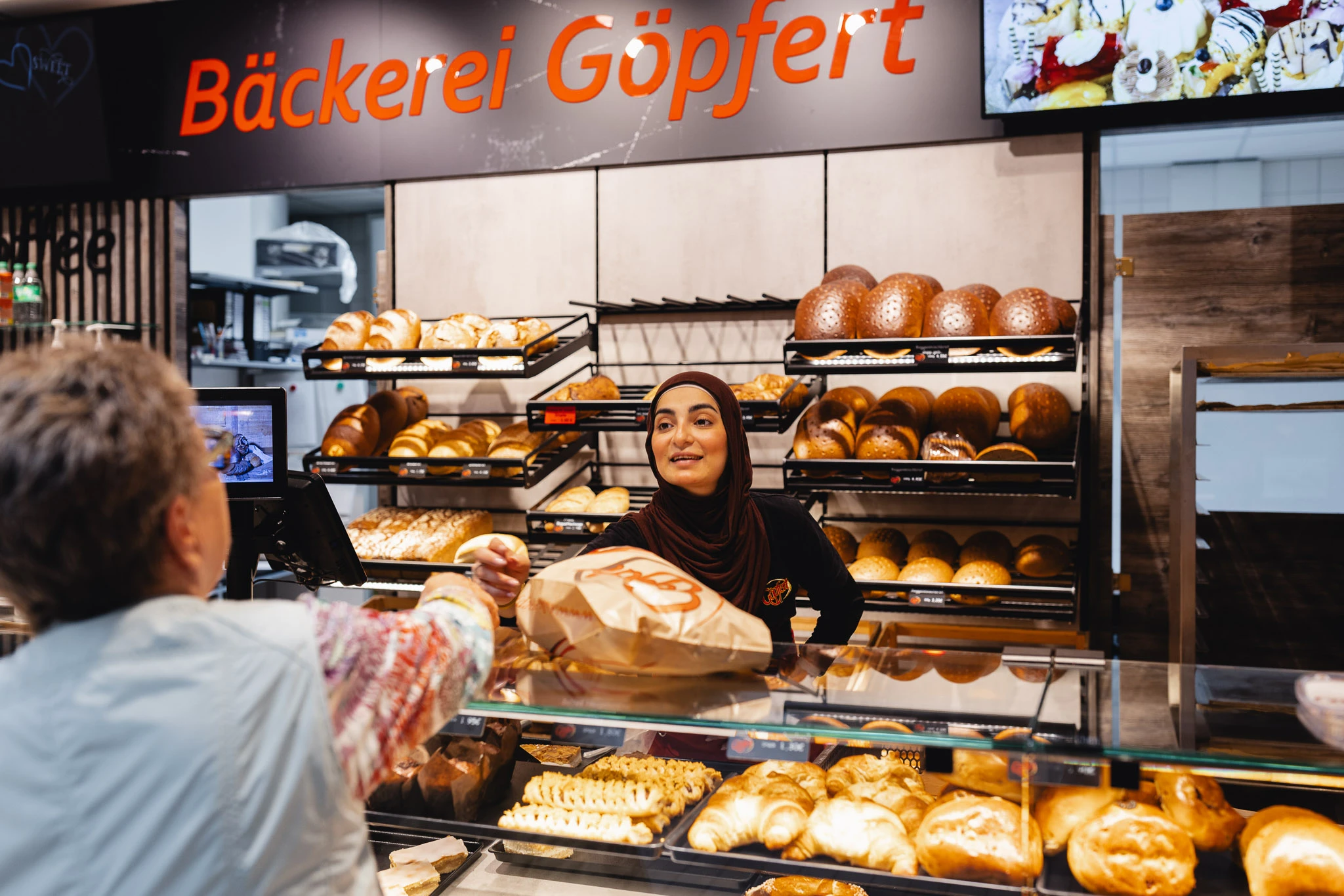 Mit einem freundlichen Lächeln bedient eine Mitarbeiterin Kunden an der Theke der Bäckerei Göpfert.