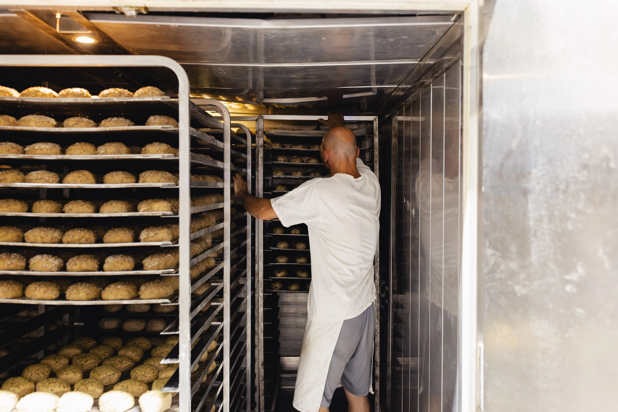 Wagen mit zahlreichen Backblechen voller frisch geformter Brötchen in dem Kühlhaus der Bäckerei.