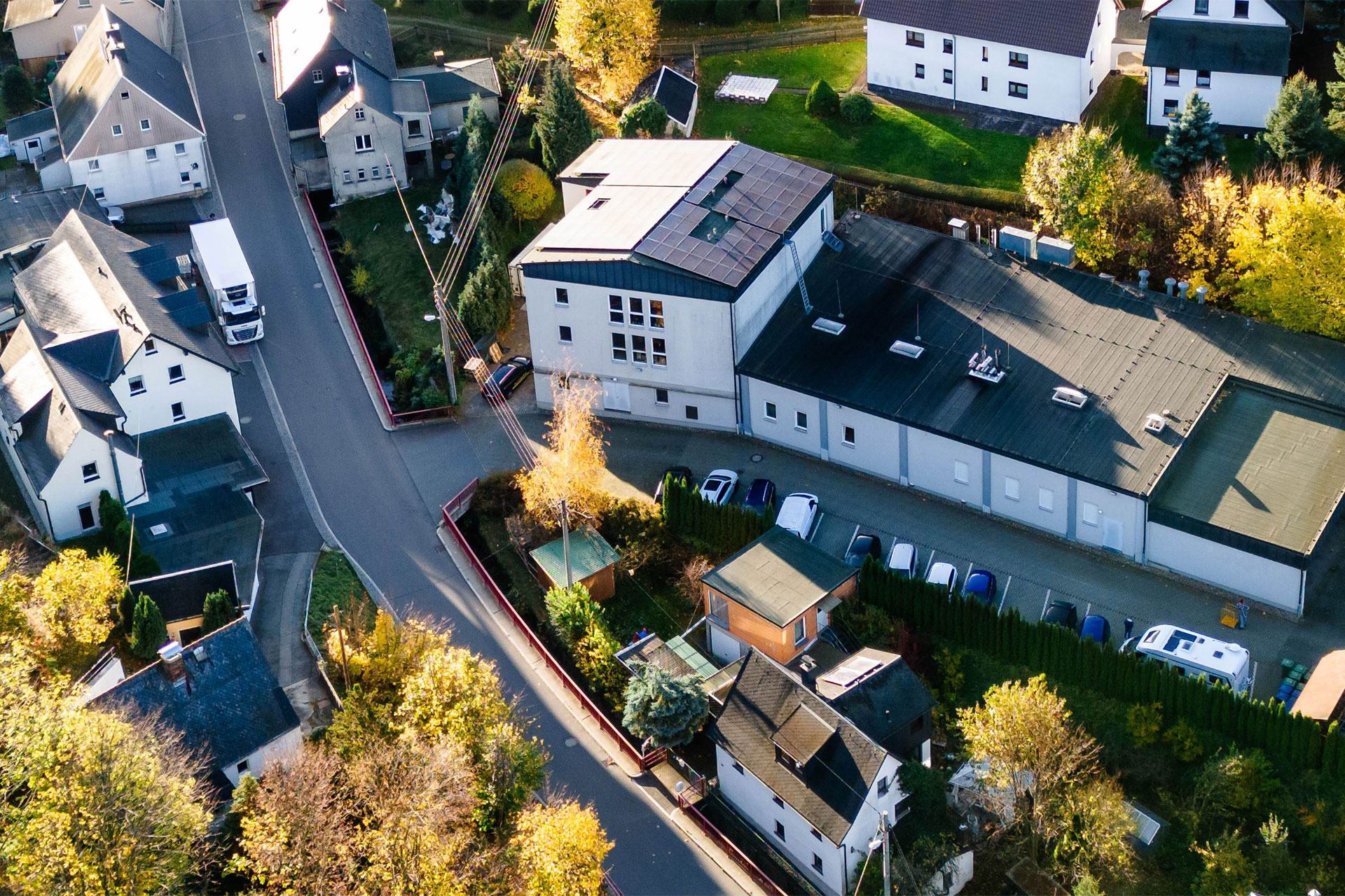 Draufsicht auf das fertiggestellte Gebäude der Bäckerei Göpfert mit Produktionsbereich, umliegenden Parkplätzen und vielen Bäumen.